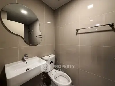 Modern bathroom with sleek design featuring a unique mirror and contemporary fixtures.