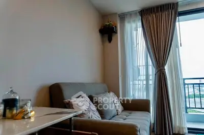 Cozy living room with plush sofa and balcony view, perfect for relaxation and enjoying natural light.