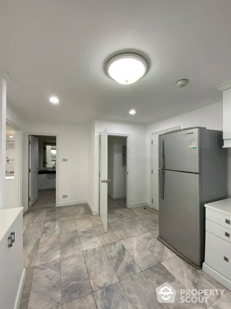 Spacious kitchen with modern fridge and elegant tile flooring in a contemporary home.