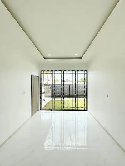 Spacious modern room with large window and sleek white flooring, perfect for natural light lovers.