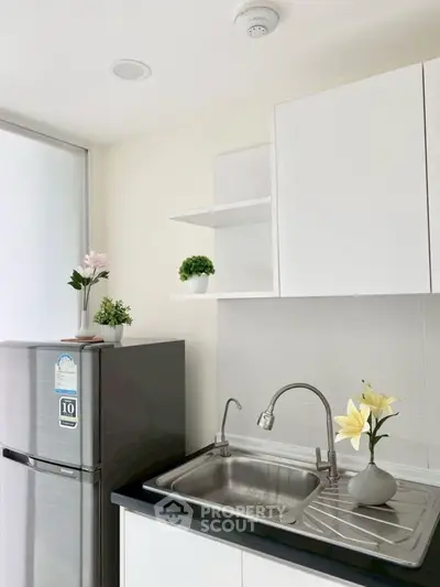 Modern kitchen with sleek white cabinets and stainless steel fridge
