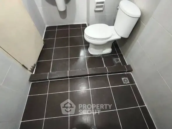 Compact bathroom with modern toilet and tiled flooring, ideal for efficient space utilization.