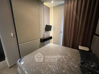 Modern bedroom with sleek design and wall-mounted TV in a stylish apartment.