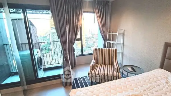 Cozy bedroom with city view and balcony access, featuring a striped armchair and modern decor.
