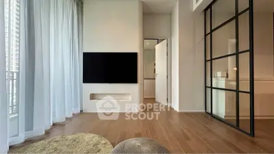 Modern living room with sleek design and large windows, featuring a wall-mounted TV and elegant flooring.