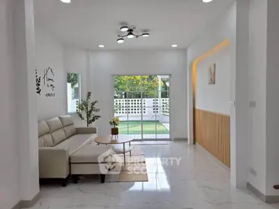 Modern living room with elegant decor and garden view, featuring a cozy sofa and stylish lighting.