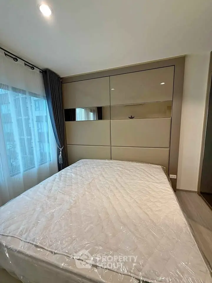 Modern bedroom with large window and stylish decor in a contemporary apartment.