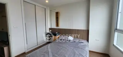 Modern bedroom with large window and built-in wardrobe in a stylish apartment.