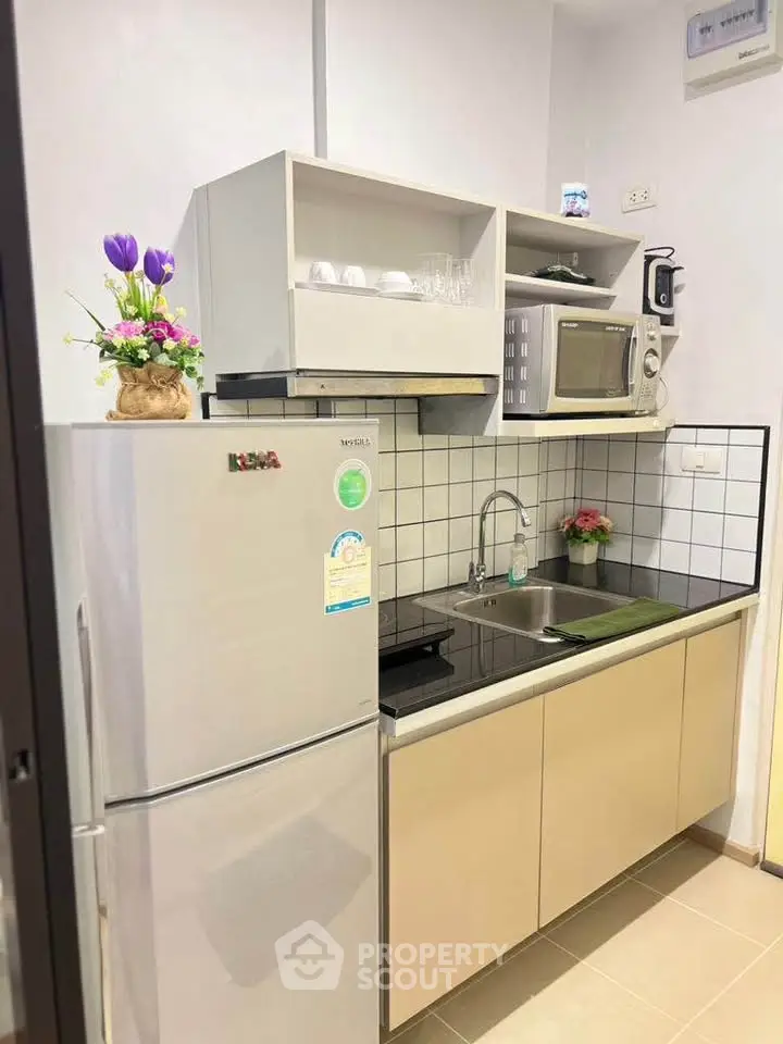 Modern compact kitchen with fridge, microwave, and sleek cabinetry