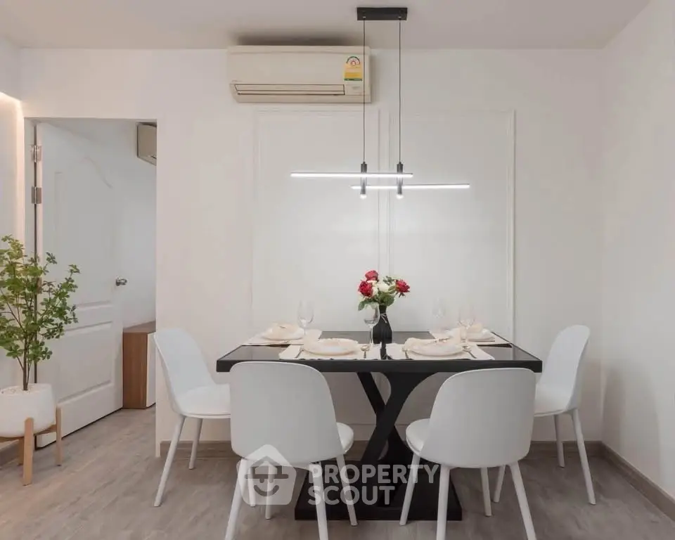 Modern dining area with sleek black table, white chairs, and minimalist decor in a stylish apartment.