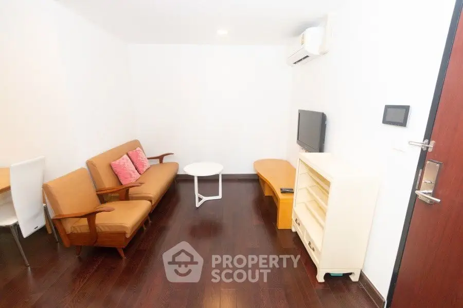 Cozy living room with wooden flooring, modern furniture, and wall-mounted TV in a stylish apartment.