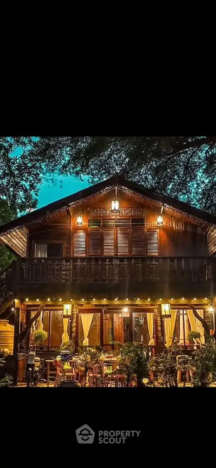 Charming wooden house with warm lighting and lush greenery, perfect for serene living.