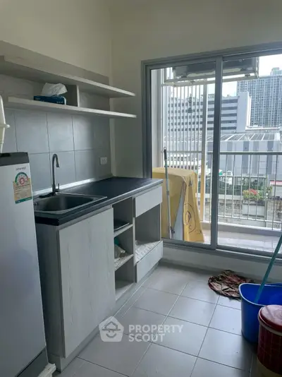 Modern kitchen with city view, featuring sleek cabinetry and large window for natural light.