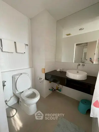 Modern bathroom with sleek fixtures and large mirror in a contemporary home.