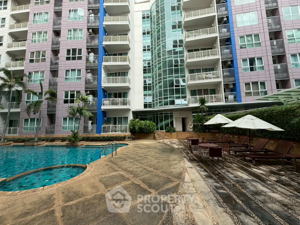 Modern apartment building with poolside lounge area and lush greenery