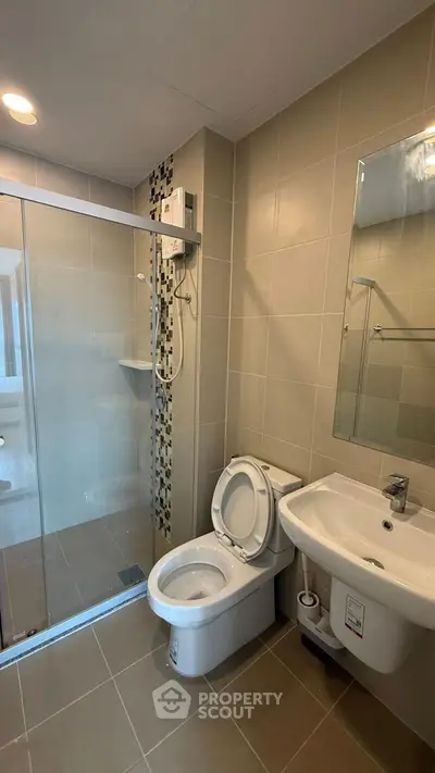 Modern bathroom with glass shower and sleek fixtures in contemporary apartment.