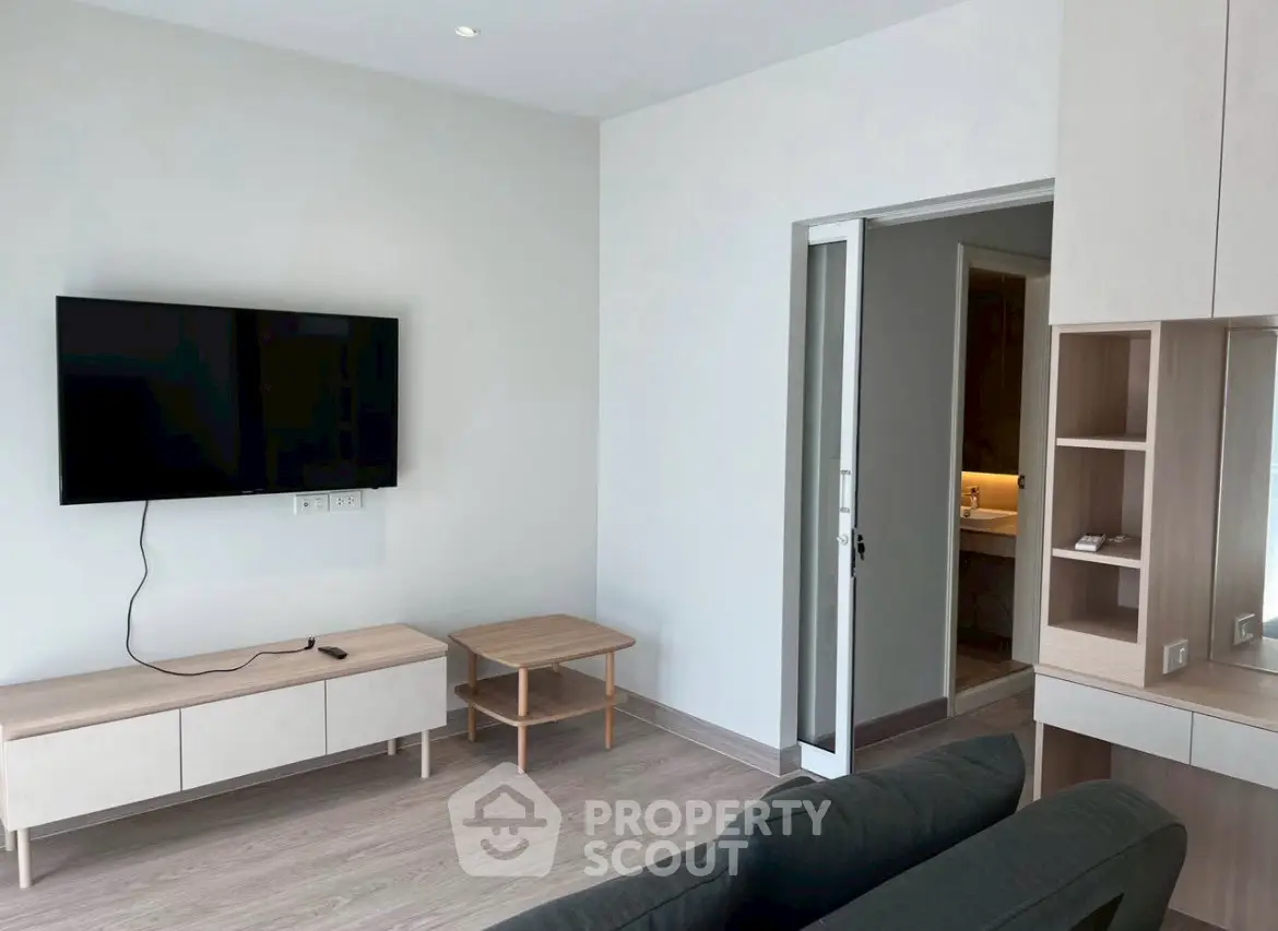 Modern living room with sleek furniture and wall-mounted TV, featuring a minimalist design.