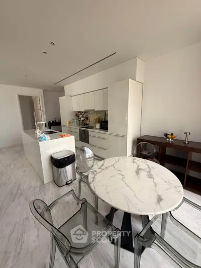 Modern kitchen with marble table and sleek white cabinetry in open layout design.