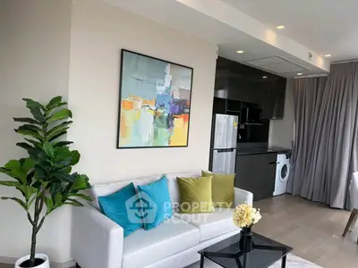 Modern living room with stylish decor, open kitchen, and washing machine in a chic apartment.