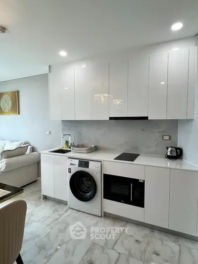 Modern kitchen with sleek white cabinets and built-in appliances in open layout