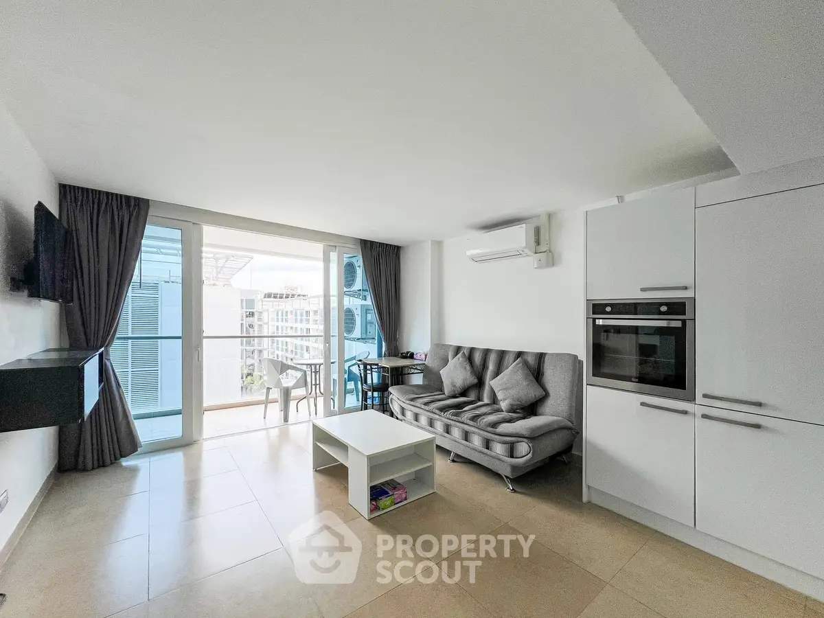Modern living room with balcony access and sleek kitchen appliances.