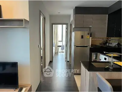Modern apartment interior with sleek kitchen and hallway leading to a bright bedroom.
