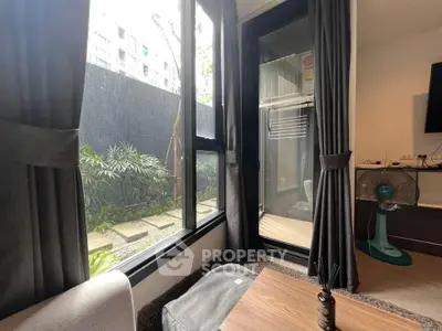 Cozy living room with garden view and modern decor, featuring large windows and stylish furnishings.