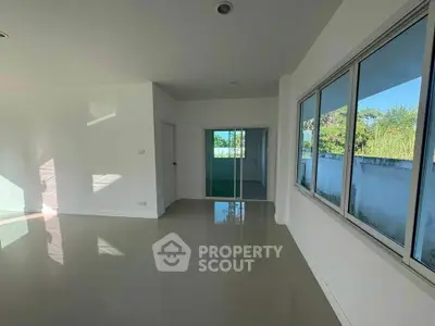 Spacious sunlit room with large windows and glossy tiled floors