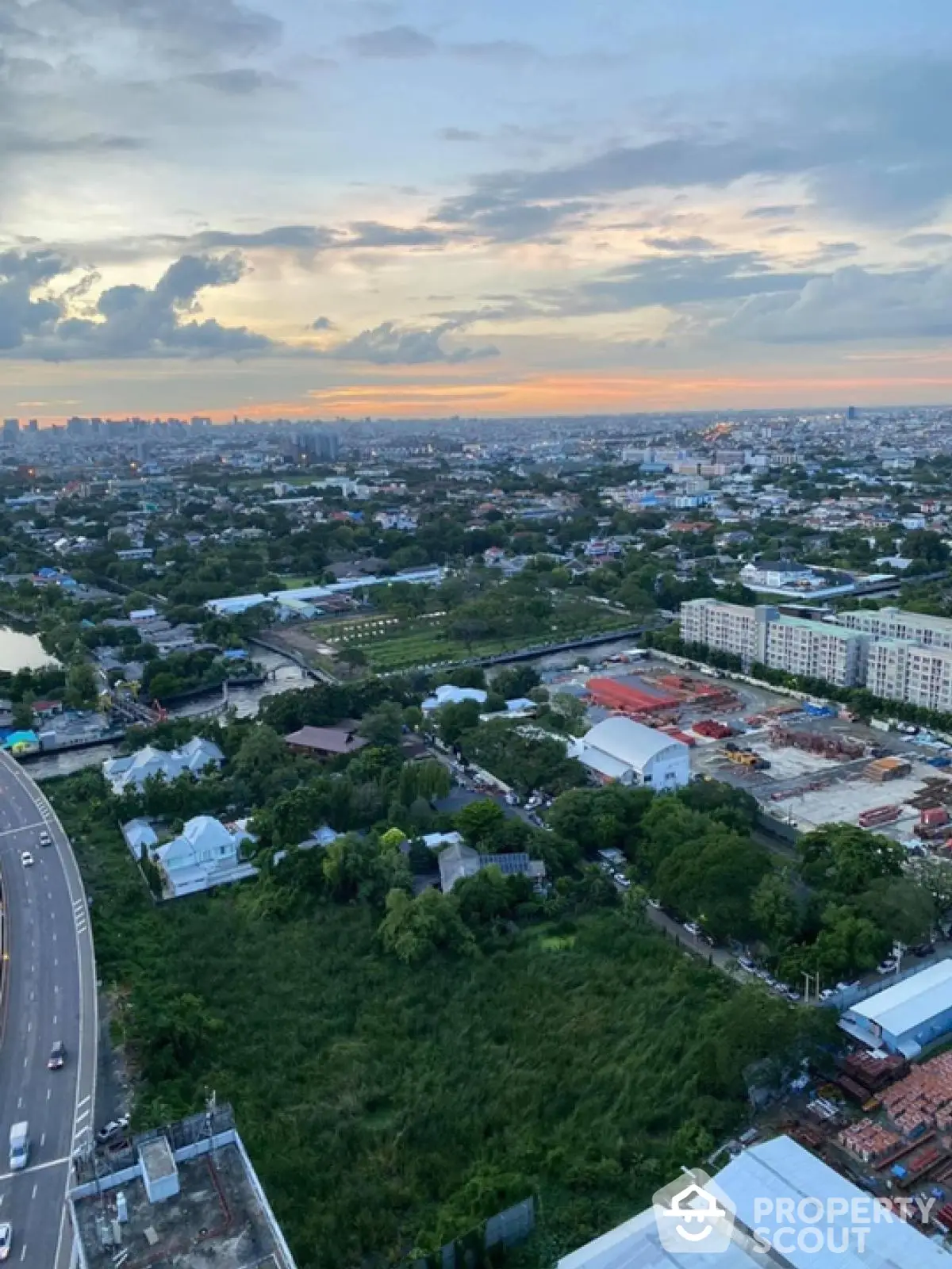 Stunning aerial view of urban landscape at sunset, showcasing city skyline and lush greenery.