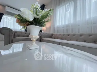 Elegant living room with plush sofas and floral centerpiece on marble table