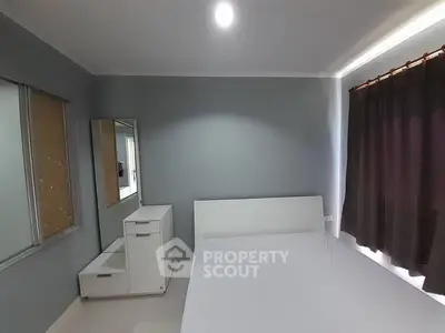 Spacious bedroom with modern minimalist design, featuring a large bed, sleek side furniture, and elegant dark curtains complementing the soft grey walls.