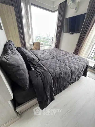 Modern bedroom with city view, featuring sleek black bedding and wall-mounted TV.