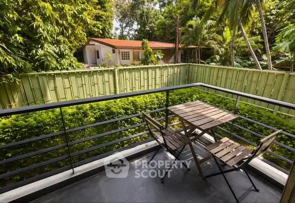Charming balcony with lush garden view and cozy seating area, perfect for relaxation.