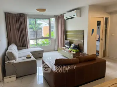 Spacious living room with modern furniture and large window offering garden view.