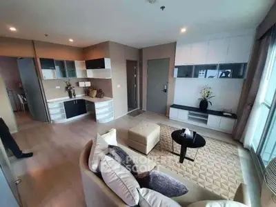 Modern living room with open kitchen, stylish decor, and cozy seating area.