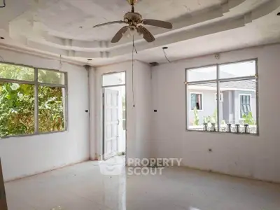 Spacious unfinished living room with ceiling fan and large windows in a modern home.