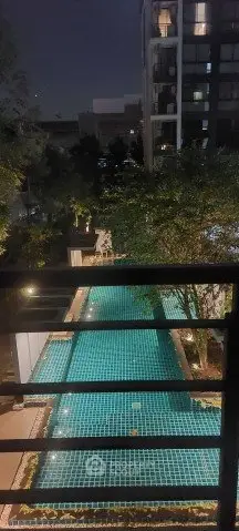 Luxurious night view of a modern apartment building with a serene outdoor pool area.