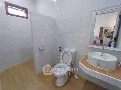 Modern bathroom with white tiles and wooden flooring, featuring a sleek sink and toilet.