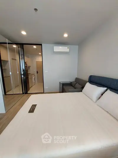 Modern bedroom with glass partition and compact kitchen in stylish apartment