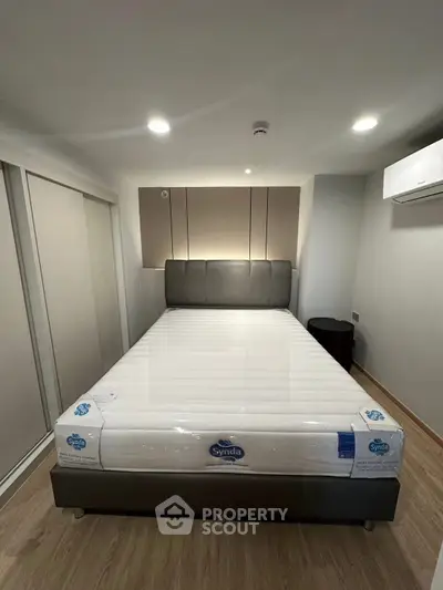 Modern bedroom with new mattress and sleek design, featuring built-in wardrobe and air conditioning.