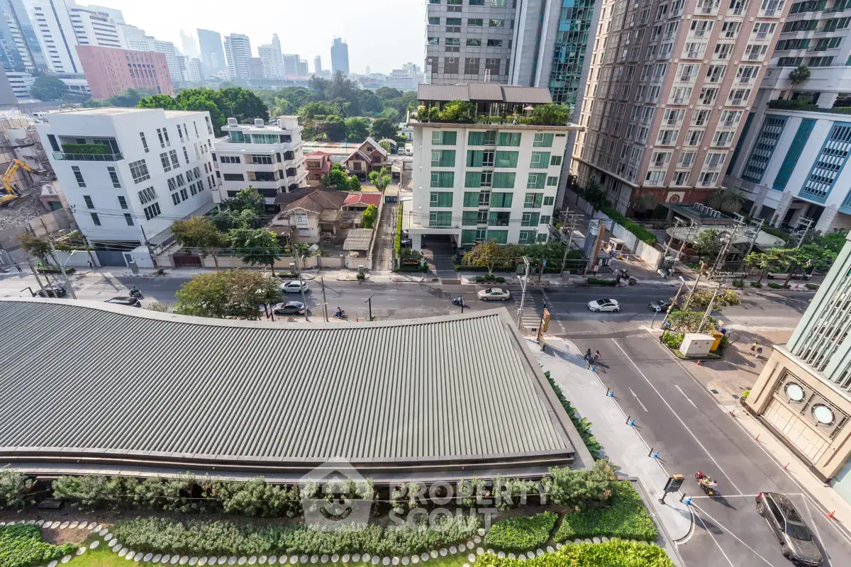 Stunning cityscape view from a high-rise building showcasing urban architecture and lush greenery.