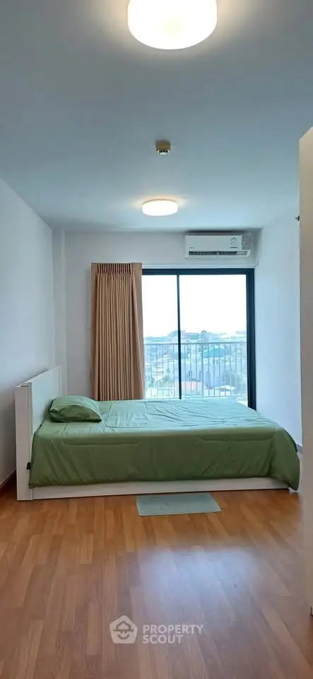 Spacious bedroom with balcony and city view, featuring wooden flooring and modern lighting.