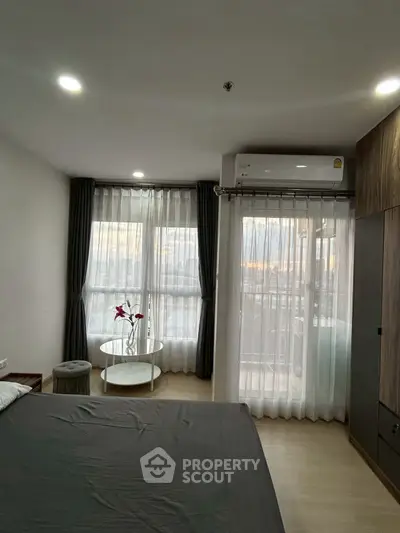 Modern bedroom with large windows and air conditioning, featuring elegant curtains and a cozy ambiance.