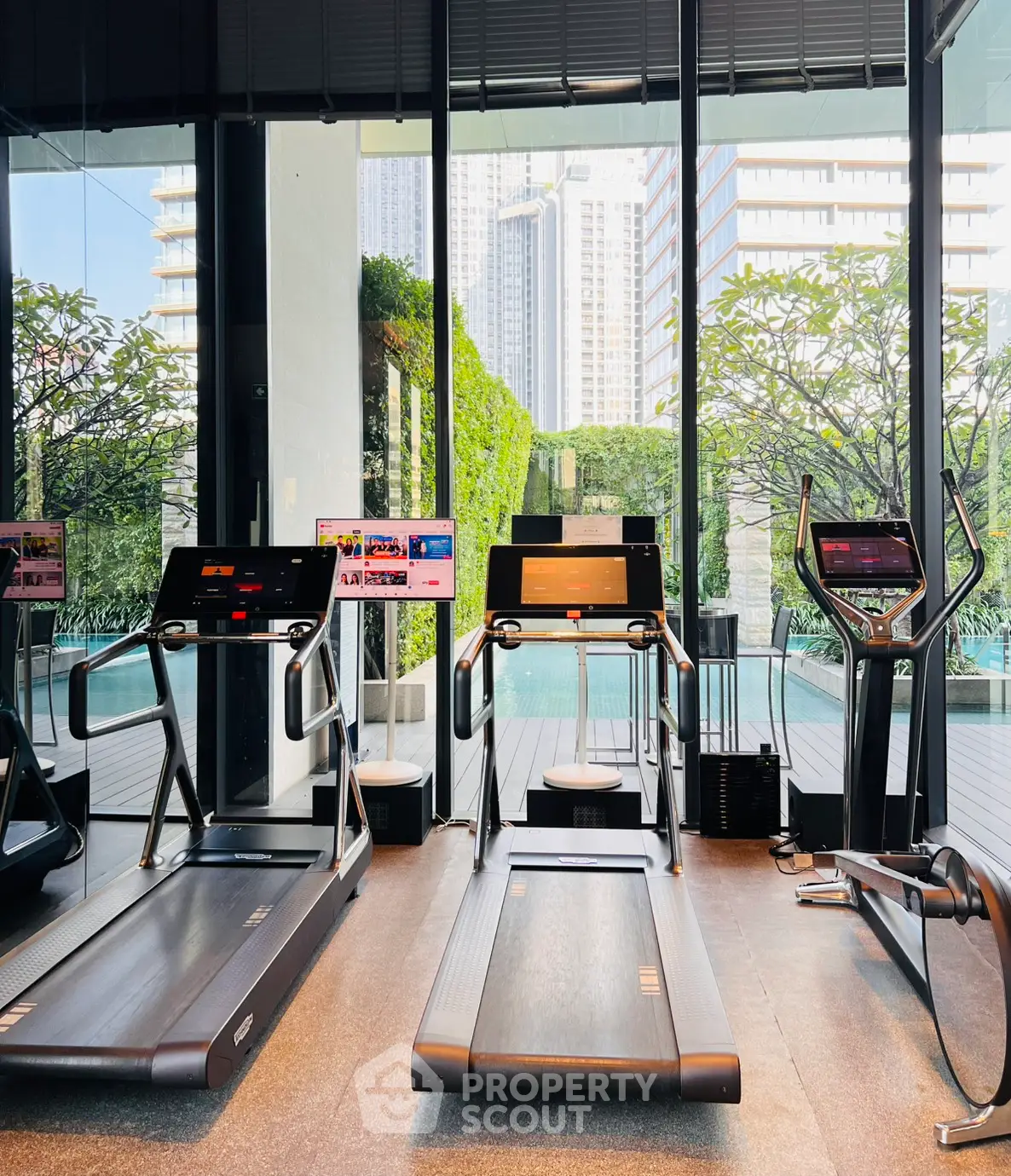 Modern gym with treadmills and pool view in luxury apartment complex