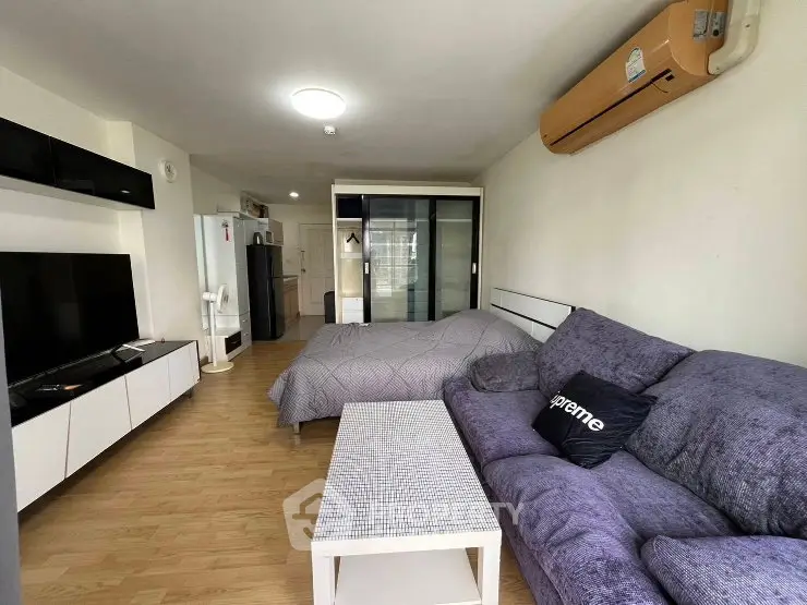 Modern studio apartment with cozy living area and sleek kitchen appliances.