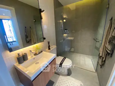 Modern bathroom with glass shower and stylish vanity in contemporary apartment.