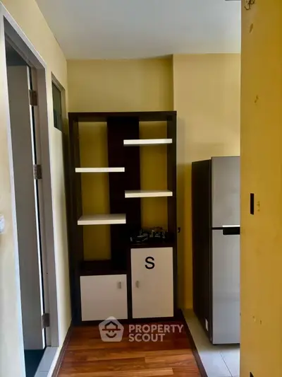 Compact kitchen with modern shelving and stainless steel fridge in cozy apartment.
