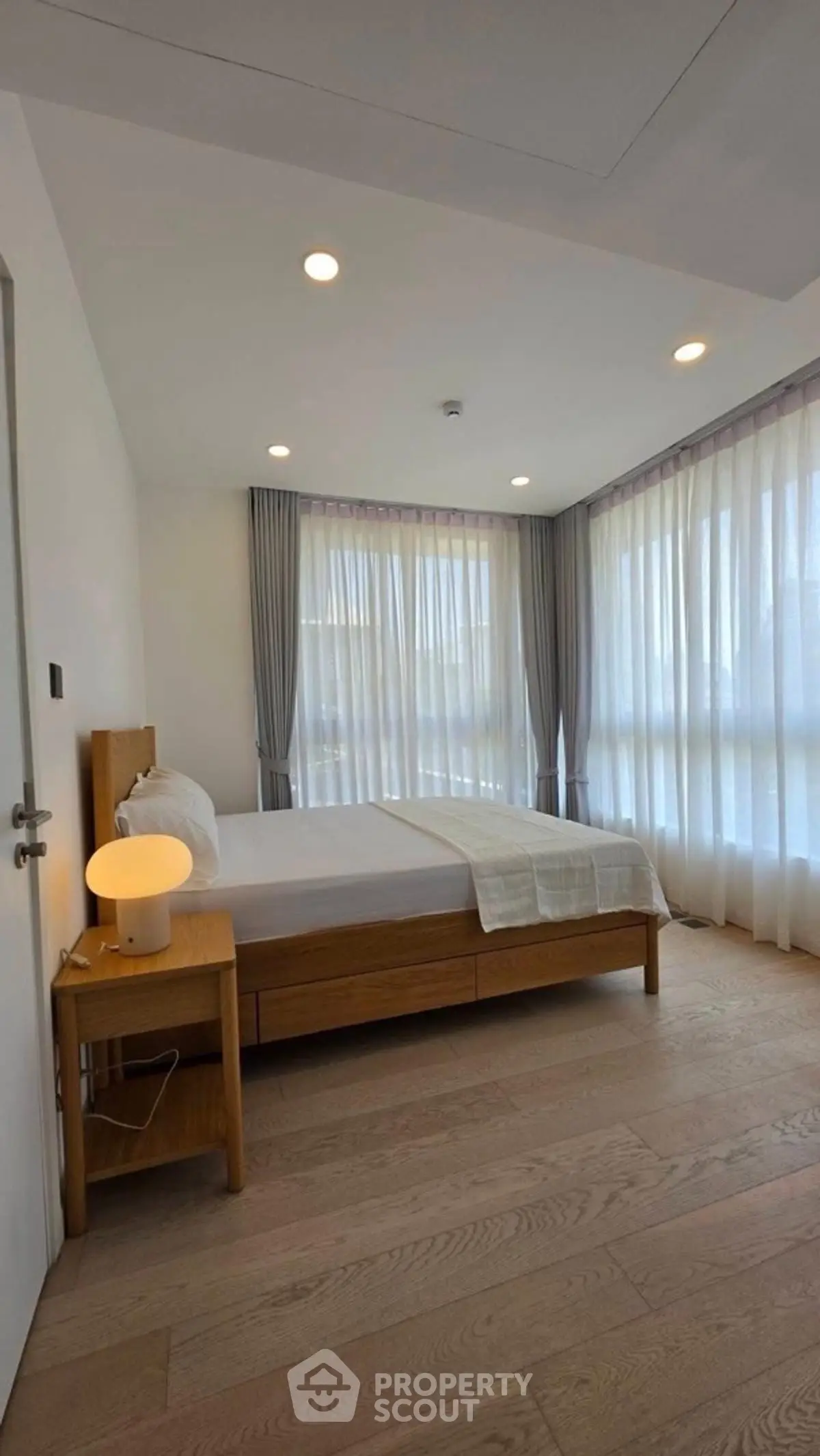 Bright and modern bedroom with large windows and wooden flooring