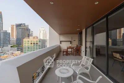 Spacious balcony with city view, modern furniture, and ample seating in urban high-rise apartment.