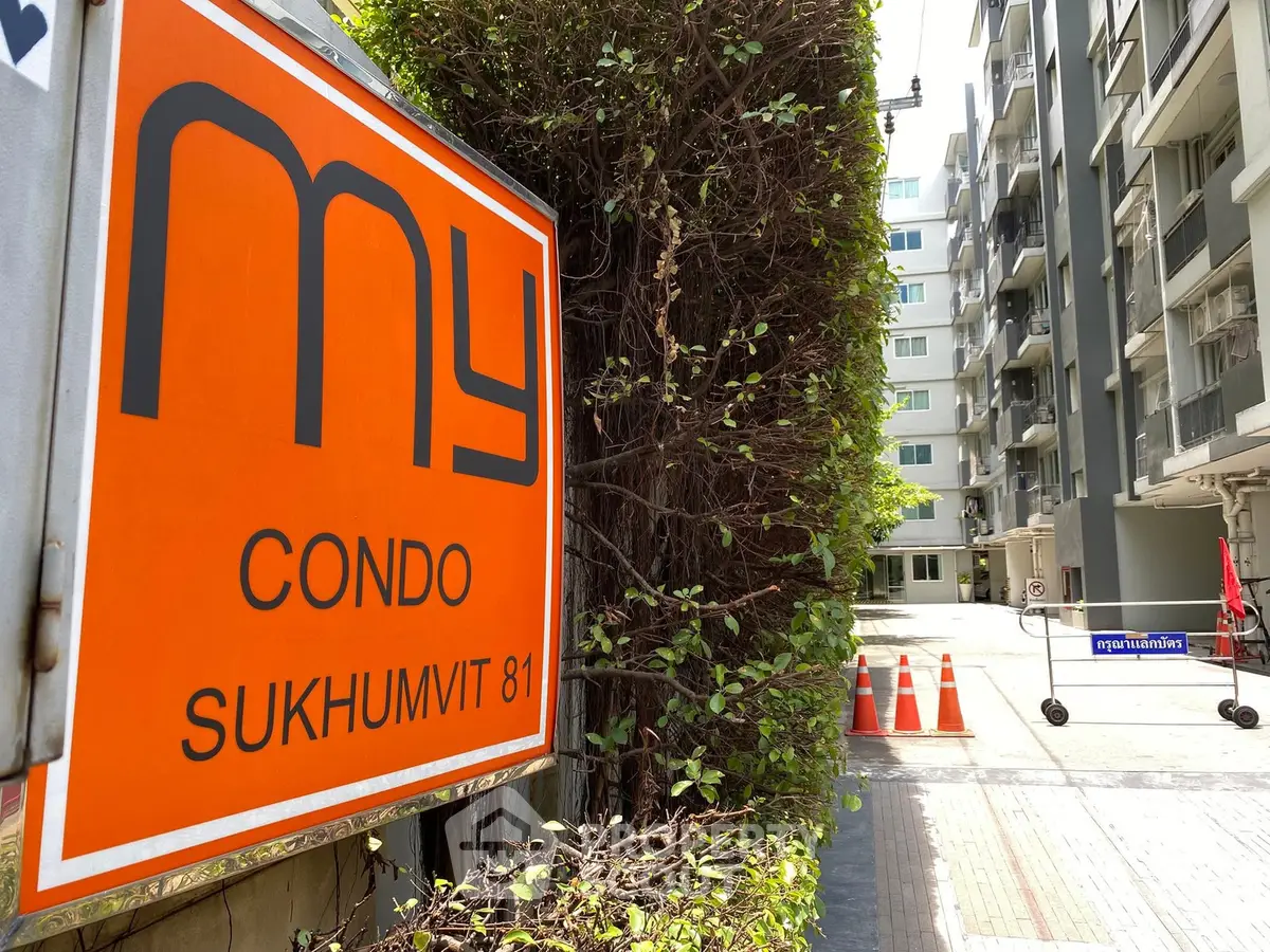 Modern condo entrance at Sukhumvit 81 with lush greenery and secure access.